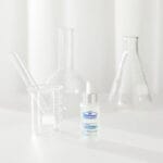 Dr. Belmeur Spot Care Ampoule 22ml - soothing serum with panthenol, beta-glucan, chaga mushroom and tea tree oil against blemishes and redness. Image of product with test tubes in the background. 