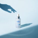 Dr. Belmeur Spot Care Ampoule 22ml - soothing serum with panthenol, beta-glucan, chaga mushroom and tea tree oil against blemishes and redness. Illustration Hand reaches for the serum. 